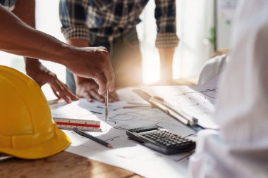 Mimarlık ekibi ofiste planlar üzerinde çalışırken bir şeyler çiziyor. Mimarlık ve Mühendislik kavramı.