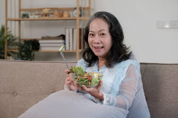 Happy old asian woman eating fresh green salad. Senior woman good healthy at home. Exercise and healthy diet concept.