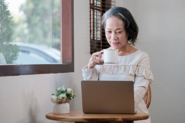 Smart asian mature middle-aged businesswoman CEO boss leader teacher using laptop, e-learning , working remotely online in home office.