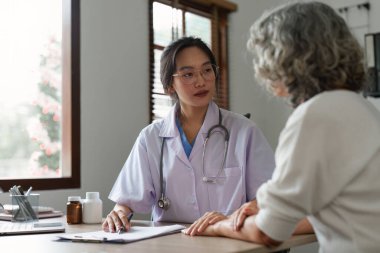 Doctor talking with elderly asian woman. Female primary care physician having conversation with older woman. Elderly Healthcare.