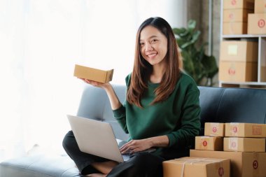 Portrait of Asian young woman SME working with a box at home. small business owner entrepreneur SME and delivery concept.