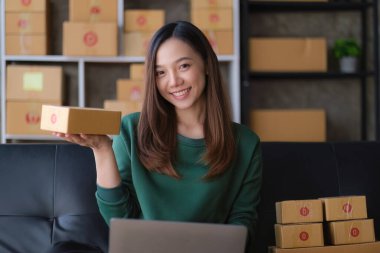 Portrait of Asian young woman SME working with a box at home. small business owner entrepreneur SME and delivery concept.