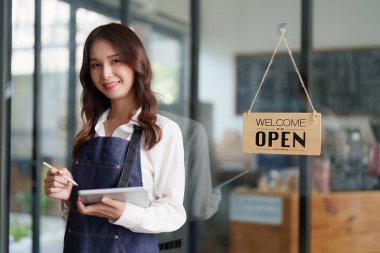 Beautiful female manager in restaurant with tablet. Man coffee shop owner with open sign. Small business concept.
