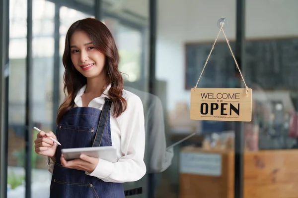 Beautiful female manager in restaurant with tablet. Man coffee shop owner with open sign. Small business concept.