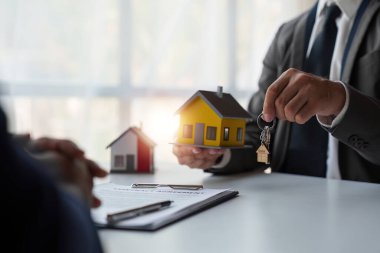 Close up of Real estate agent to buy houses and land are delivering keys and houses. Discussion with a real estate agent.