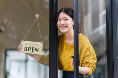 Beautiful female manager in restaurant with tablet. Woman coffee shop owner with open sign. Small business concept.