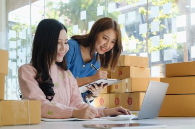 Asyalı küçük işletme sahibi ev ofisindeki arkadaşıyla birlikte çalışıyor. Ticari perakende pazarı ve çevrimiçi pazarlama dağıtımı, KOBİ e-ticaret kavramı