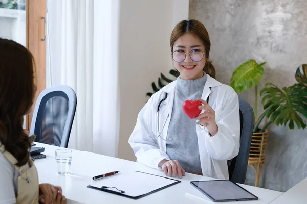 Cardiologist holding red heart in private clinic. Medical technology diagnostics of heart concept