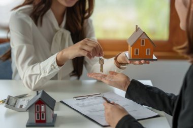 The real estate agent or agency giving house key to customer after signing agreement contract. Property concept