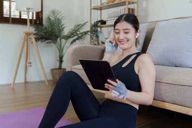 Sağlıklı Asyalı kadın evde yoga yapıyor. Ev kavramında zaman harcamak ve dijital tablet oynamak.