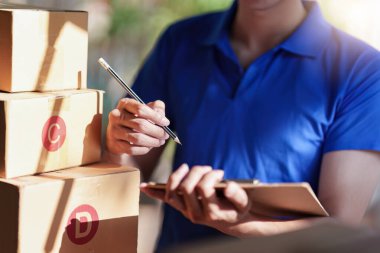 Paket ve teslimat konsepti olan Asyalı kurye. Panoda kontrol listesi olan teslimatçı..