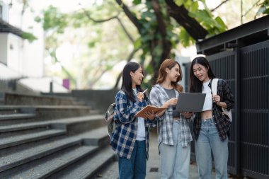 Beautiful young Asian woman college student with friends at outdoors. College student working on the college campus.