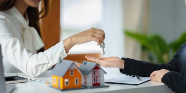 The real estate agent or agency giving house key to customer after signing agreement contract. Property concept