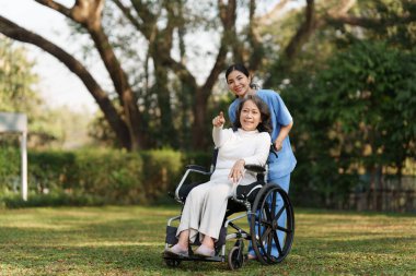 Elderly asian senior woman on wheelchair with nurse. Nursing home hospital garden concept.