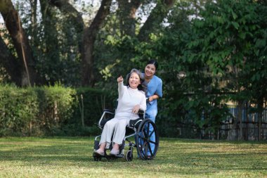 Elderly asian senior woman on wheelchair with nurse. Nursing home hospital garden concept