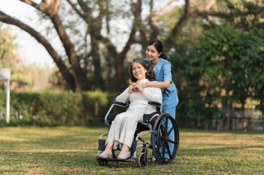 Elderly asian senior woman on wheelchair with nurse. Nursing home hospital garden concept