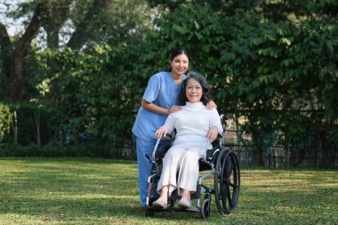 Elderly asian senior woman on wheelchair with nurse. Nursing home hospital garden concept