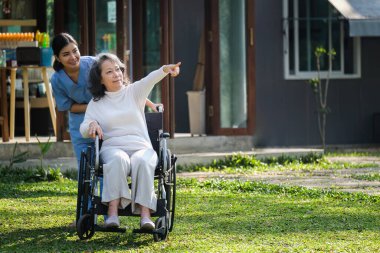Elderly asian senior woman on wheelchair with nurse. Nursing home hospital garden concept