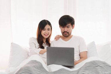 Beautiful asian couple in love and smiling sitting on bed. Romantic moment, relationships, family concept