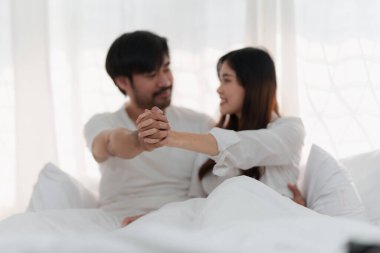 Beautiful asian couple in love and smiling sitting on bed. Romantic moment, relationships, family concept