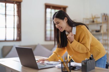 Young happy woman using laptop and celebrating victory and success, have good news, job celebrating achievement
