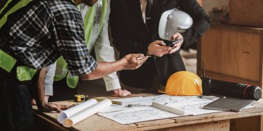 Mimarlık planının planlarıyla çalışan mimar takımı, bir inşaat projesi çizen mühendis, yeşil enerji konsepti.