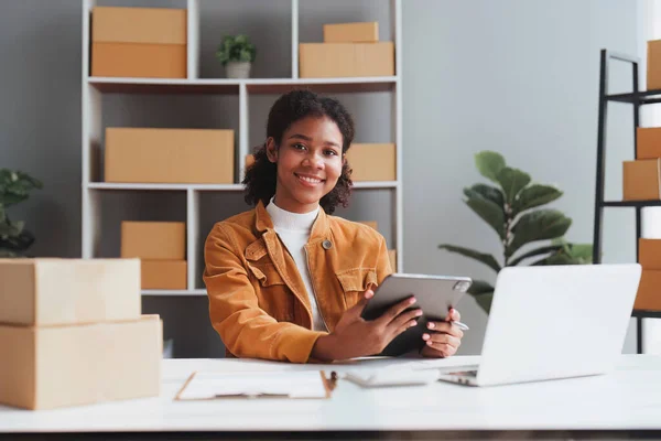 stock image American African entrepreneur smile and use a tablet to check online order. Successful SME entrepreneur concept.