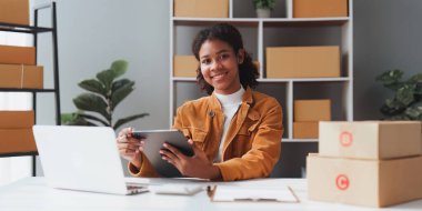 Amerikalı Afrikalı girişimci gülümser ve online siparişi kontrol etmek için bir tablet kullanır. Başarılı KME girişimci kavramı.