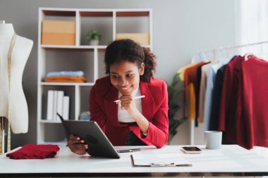 Stüdyoda dizüstü bilgisayarla çalışan Amerikalı Afrikalı moda tasarımcısı.