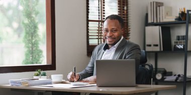 Gülümseyen Amerikalı Afrikalı finansal raporlar hazırlar ve yıllık rakamları inceler, karı analiz eder. Muhasebeci mali durumun durumunu kontrol ediyor.