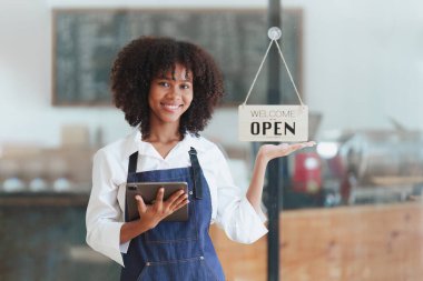 Güzel Amerikalı Afrikalı kafe sahibi kafede dikiliyor ve dijital tablet kullanıyor. Kafede, restoranda çalışmak..