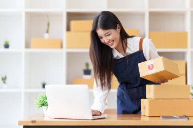 Küçük işletmeler KOBİ 'nin kadın girişimcileri, kutuları paketlemek, müşterilere satmak ve iş fikirlerini çevrimiçi olarak satmak için online siparişleri kontrol ediyorlar.