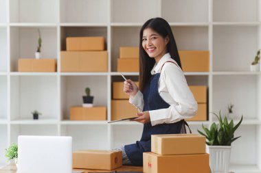 Küçük işletmeler KOBİ 'nin kadın girişimcileri, kutuları paketlemek, müşterilere satmak ve iş fikirlerini çevrimiçi olarak satmak için online siparişleri kontrol ediyorlar.
