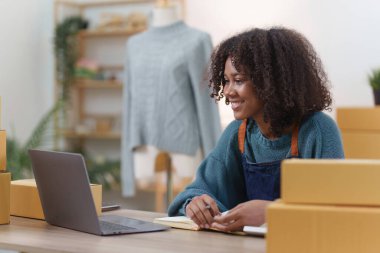 Amerikalı Afrikalı girişimci gülümseyip online siparişleri kontrol ediyor. Başarılı KME girişimci kavramı.