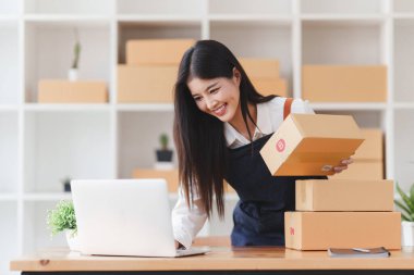 Küçük işletmeler KOBİ 'nin kadın girişimcileri, kutuları paketlemek, müşterilere satmak ve iş fikirlerini çevrimiçi olarak satmak için online siparişleri kontrol ediyorlar.