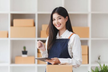 Küçük işletmeler KOBİ 'nin kadın girişimcileri, kutuları paketlemek, müşterilere satmak ve iş fikirlerini çevrimiçi olarak satmak için online siparişleri kontrol ediyorlar.