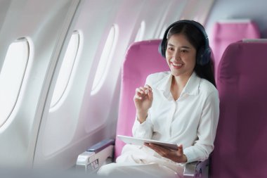 Uçakta dijital tabletle çalışan Asyalı güzel bir iş kadını. çalışma, seyahat, iş konsepti.