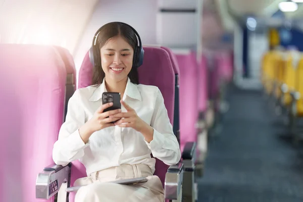Piękna Azjatycka Bizneswoman Słuchać Muzyki Przez Telefon Komórkowy Podczas Lotu — Zdjęcie stockowe