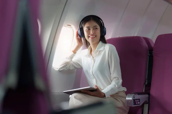 Beautiful Asian businesswoman working with digital tablet in aeroplane. working, travel, business concept.