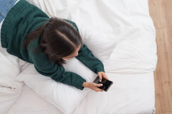 stock image Smiling young asian woman using smart phone in bedroom at home. lifestyle, woman lying on bed.