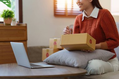 Küçük işletmeler KOBİ 'nin kadın girişimcileri, kutuları paketlemek, müşterilere satmak ve iş fikirlerini çevrimiçi olarak satmak için online siparişleri kontrol ediyorlar.