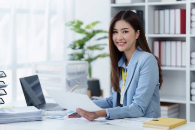 Dizüstü bilgisayarda çalışan ve belge, vergi, takas, araştırma, muhasebe ve mali danışman konsepti üzerinde çalışan muhasebeci kadın.