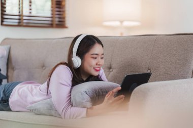 Çekici Asyalı kadın rahat oturma odasında dinleniyor ve dijital tablet kullanıyor, Rahat, Kanepe, Yaşam Tarzı.