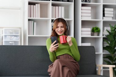 Çekici Asyalı kadın rahat oturma odasında dinleniyor ve dizüstü bilgisayar kullanıyor..