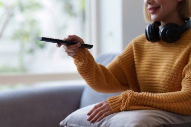 Oturma odasındaki kanepede dinlenen genç bir kadın. Televizyondaki kadın filmi dairedeki koltukta oturuyor, boş zamanlarında..