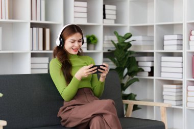 Çekici Asyalı kadın rahat oturma odasında dinleniyor ve cep telefonu kullanıyor, Rahat, Kanepe, Yaşam Tarzı.