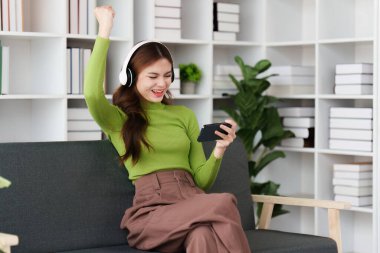 Çekici Asyalı kadın rahat oturma odasında dinleniyor ve cep telefonu kullanıyor, Rahat, Kanepe, Yaşam Tarzı.