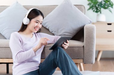 Çekici Asyalı kadın rahat oturma odasında dinleniyor ve dijital tablet kullanıyor, Rahat, Kanepe, Yaşam Tarzı.