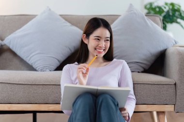 Çevrimiçi eğitim, e-öğrenme. Şık giyinmiş Asyalı bir kadın, dizüstü bilgisayar kullanıyor, online dersler dinliyor, notlar alıyor, evde online çalışmalar yapıyor..