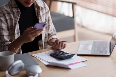 Asyalı muhasebe uzmanı ev faturalarını hesaplıyor, ev faturalarını inceliyor ve analiz ediyor ve vergi beyannamelerini dolduruyor...